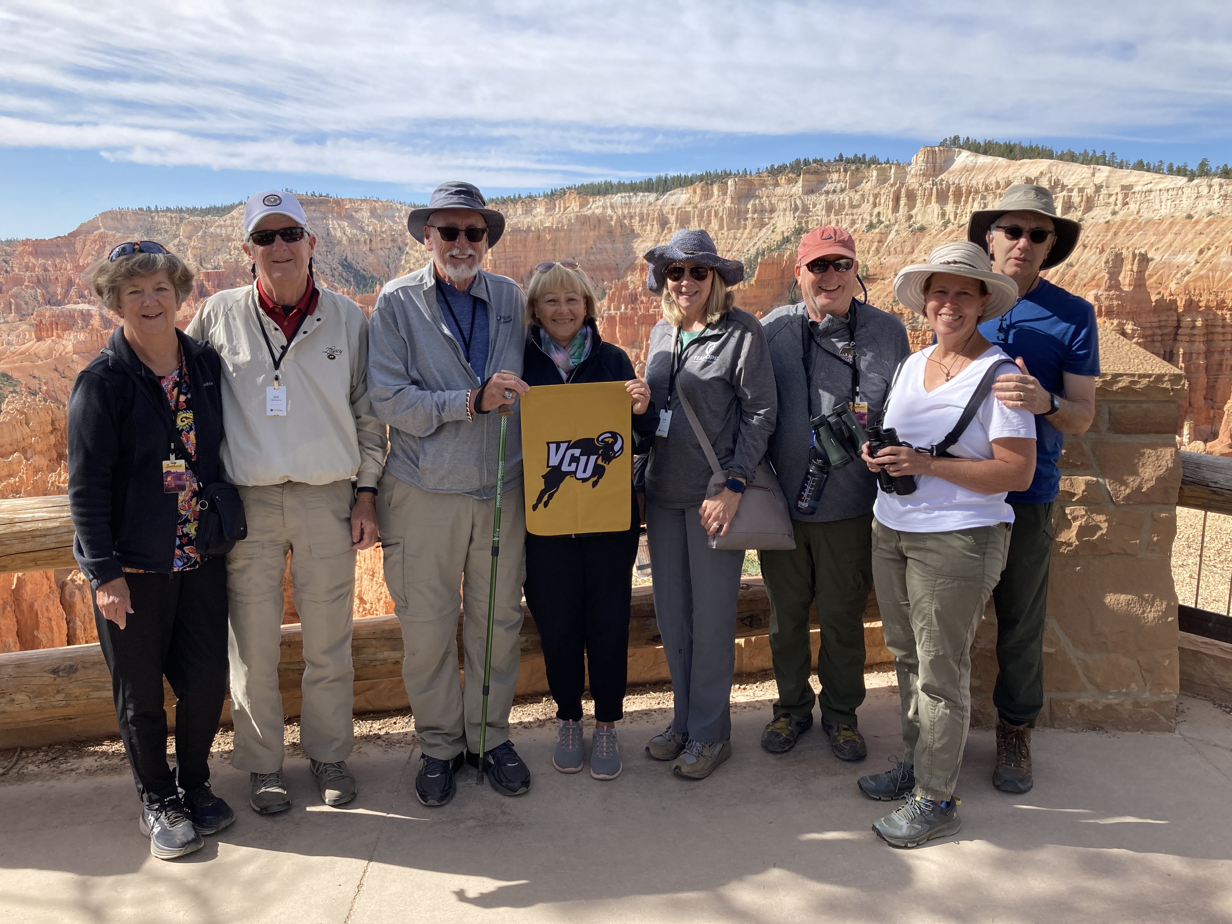 Several travelers hold a VCU flag in front of mountains